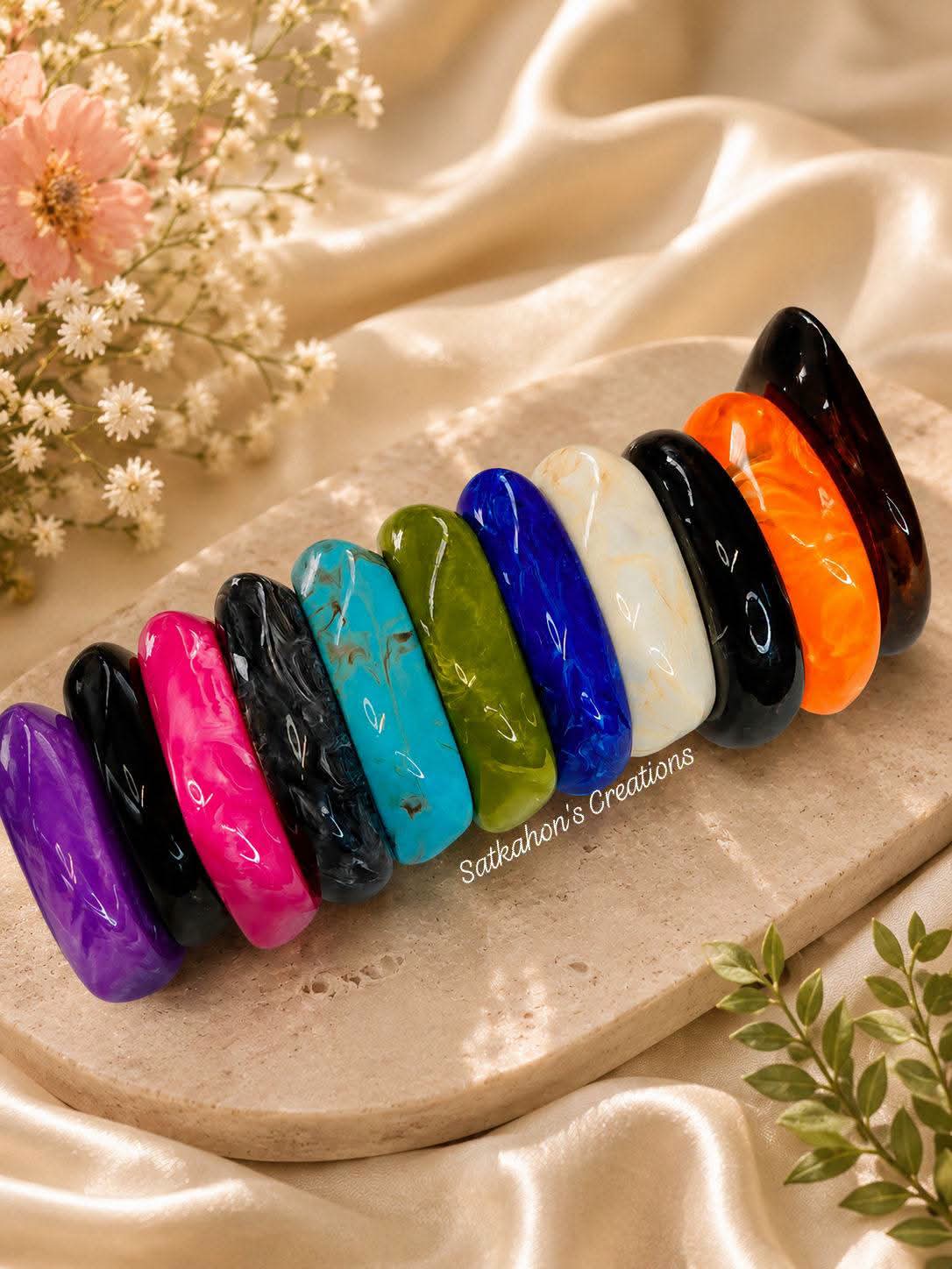 A vibrant stack of colourful bangles on a stone jewellery stand